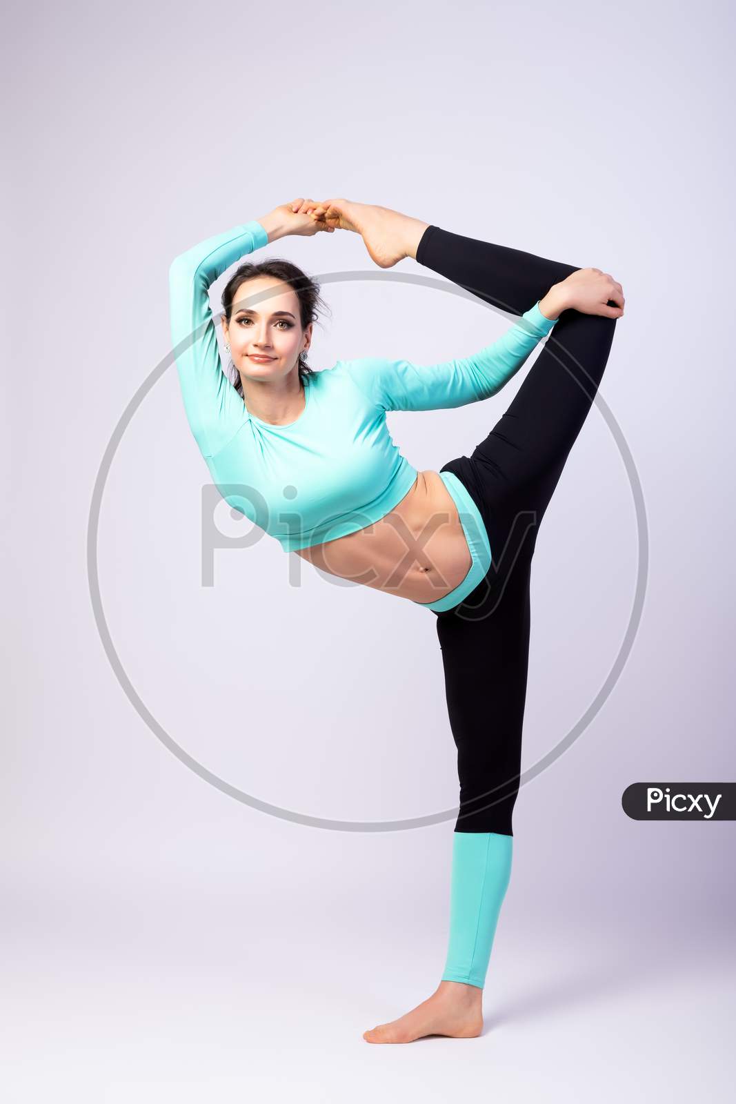 A Young Woman Coach Stretch   On A  White Isolated Background In Studio. The Concept Of Sports And Meditation. Training For Stretching
