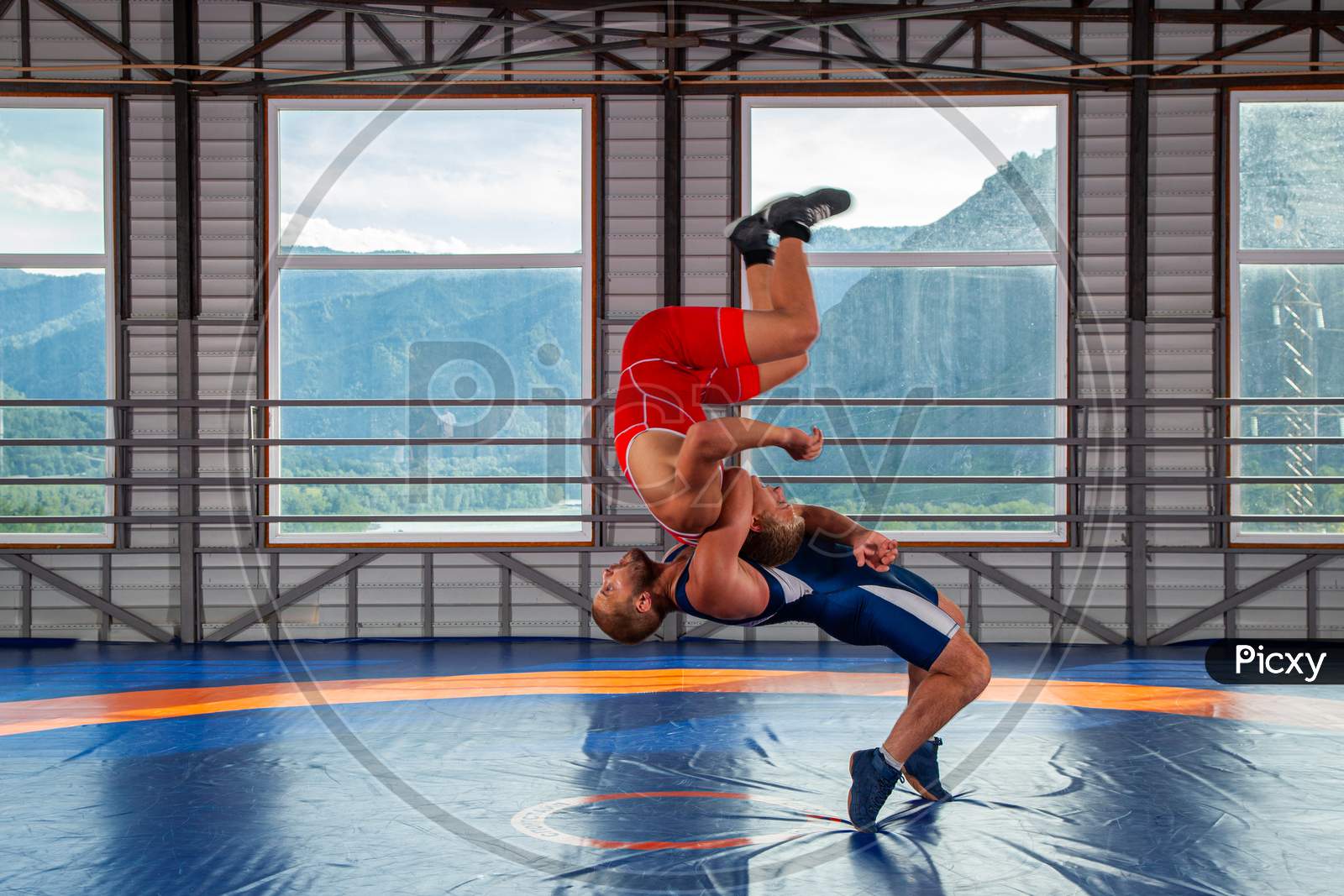 Greco-Roman Wrestling Training, Grappling. Two Greco-Roman  Wrestlers In Red And Blue Uniform Wrestling  On A Wrestling Carpet In The Gym.Training And Practicing Sports Throws