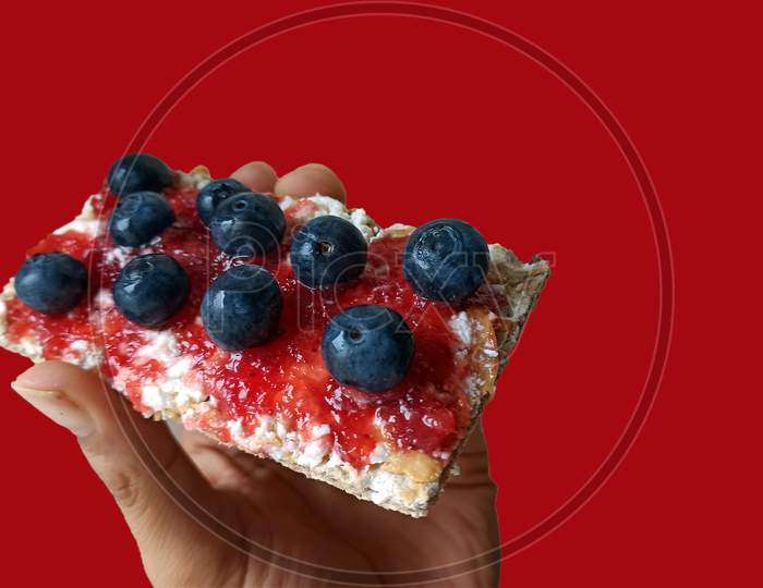 Healthy Delicious Breakfast Concept Of Fiber Crunchy Bread With Peanut Butter, Berry Jam And Bunch Of Blueberry On Top Against Bright Red Background For Copy Paste Text. Light Snacks For Fitness Diet.
