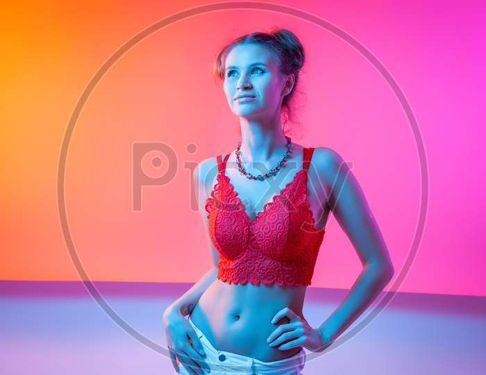 Cinematic Night Portrait Of Woman In  Neon. High Fashion Model Girl In Colorful Bright Neon Lights Posing In Studio, Portrait Of Beautiful Woman In Top And Jeans.