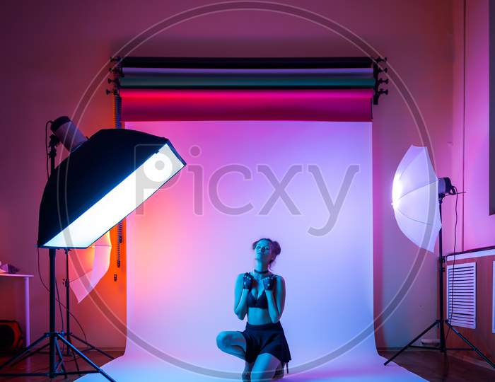 Backstage: Model Woman With In Black Underwear, Pantyhose, Skirt Posing In Attractive Position In Colorful Bright Neon Blue And Pink Lights In Studio. Fashion Concept