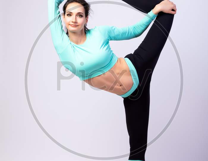 A Young Woman Coach Stretch   On A  White Isolated Background In Studio. The Concept Of Sports And Meditation. Training For Stretching