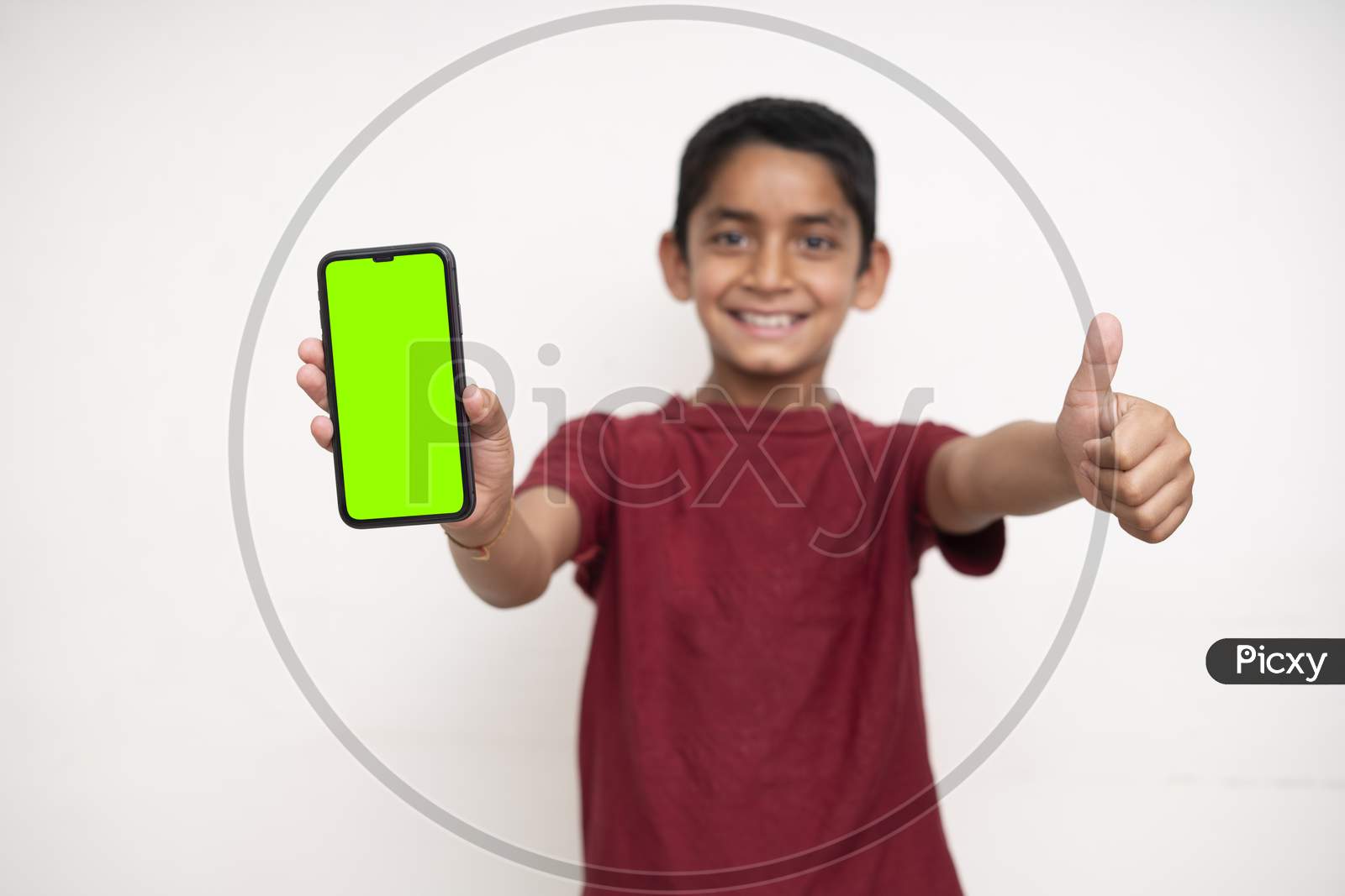 Young Indian Kid Holding A Phone In His Hands With A Green Screen Standing On A White Isolated Background With Copy Space.