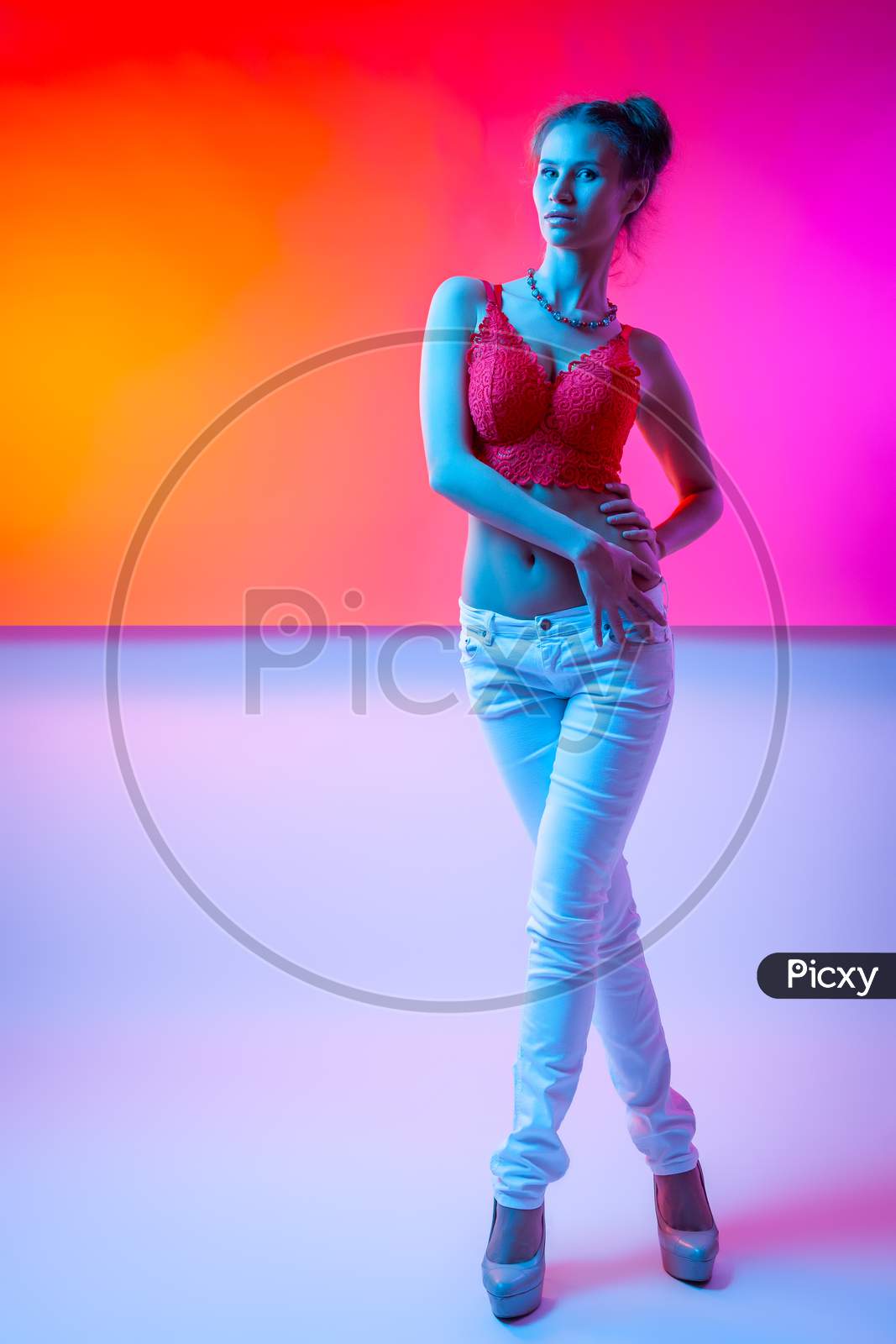 Cinematic Night Portrait Of Woman In  Neon. High Fashion Model Girl In Colorful Bright Neon Lights Posing In Studio, Portrait Of Beautiful Woman In   Top And Trousers.