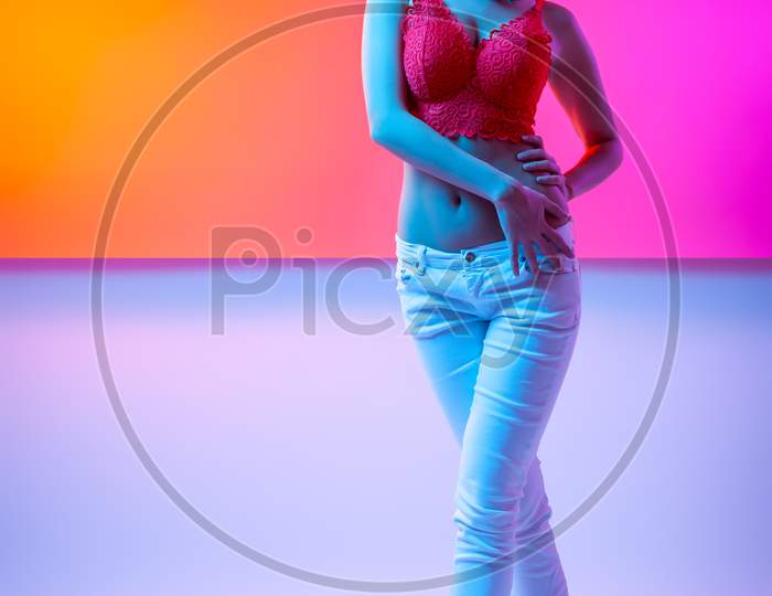 Cinematic Night Portrait Of Woman In  Neon. High Fashion Model Girl In Colorful Bright Neon Lights Posing In Studio, Portrait Of Beautiful Woman In   Top And Trousers.