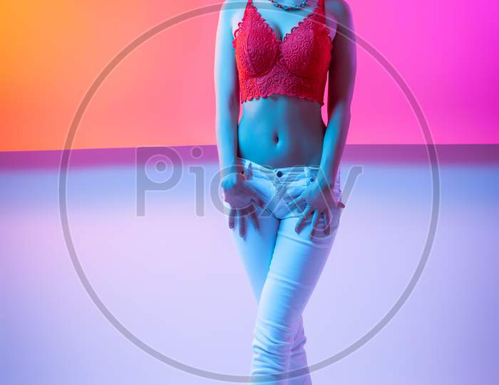 Attractive  Long-Haired Girl, Stylish Fashion. Creative Colorful Neon Portrait . Beautiful Girl A Red Underwear And Jeans Posing. Cinematic Night Portrait Of Woman In  Neon.