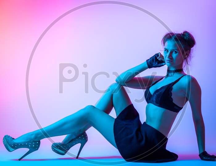 Attractive  Long-Haired Girl, Stylish Fashion. Design Art Concept. Creative Colorful Bright Neon Portrait . Beautiful Girl In Lingerie And Skirt Posing. Cinematic Night Portrait Of Woman In  Neon.
