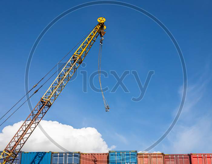 A Cargo Crane Operates In The Territory Of The Container Freight Yard: A Lot Of Metal Containers For Storing Goods Of Different Colors, Stacked In Rows On Top Of Each Other.