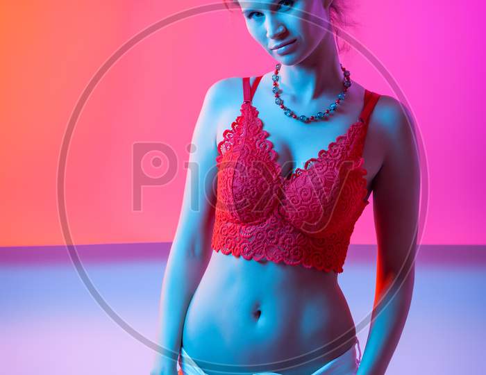 Cinematic Night Portrait Of Woman In  Neon. High Fashion Model Girl In Colorful Bright Neon Lights Posing In Studio, Portrait Of Beautiful Woman In Lingerie And Jeans