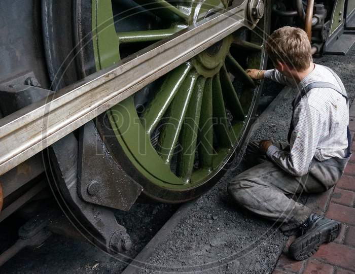 Young Man Cleaning A Steam Train Wheel