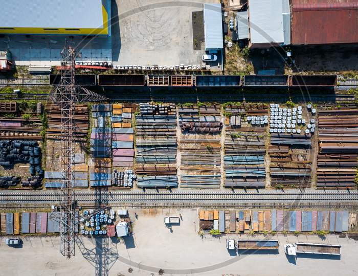Top View Of The Industrial Zone: Railway Rails, Garages, Warehouses, Truck,Metal. The Concept Of Storage Of Goods By Importers, Exporters, Wholesalers, Transport Enterprises, Customs