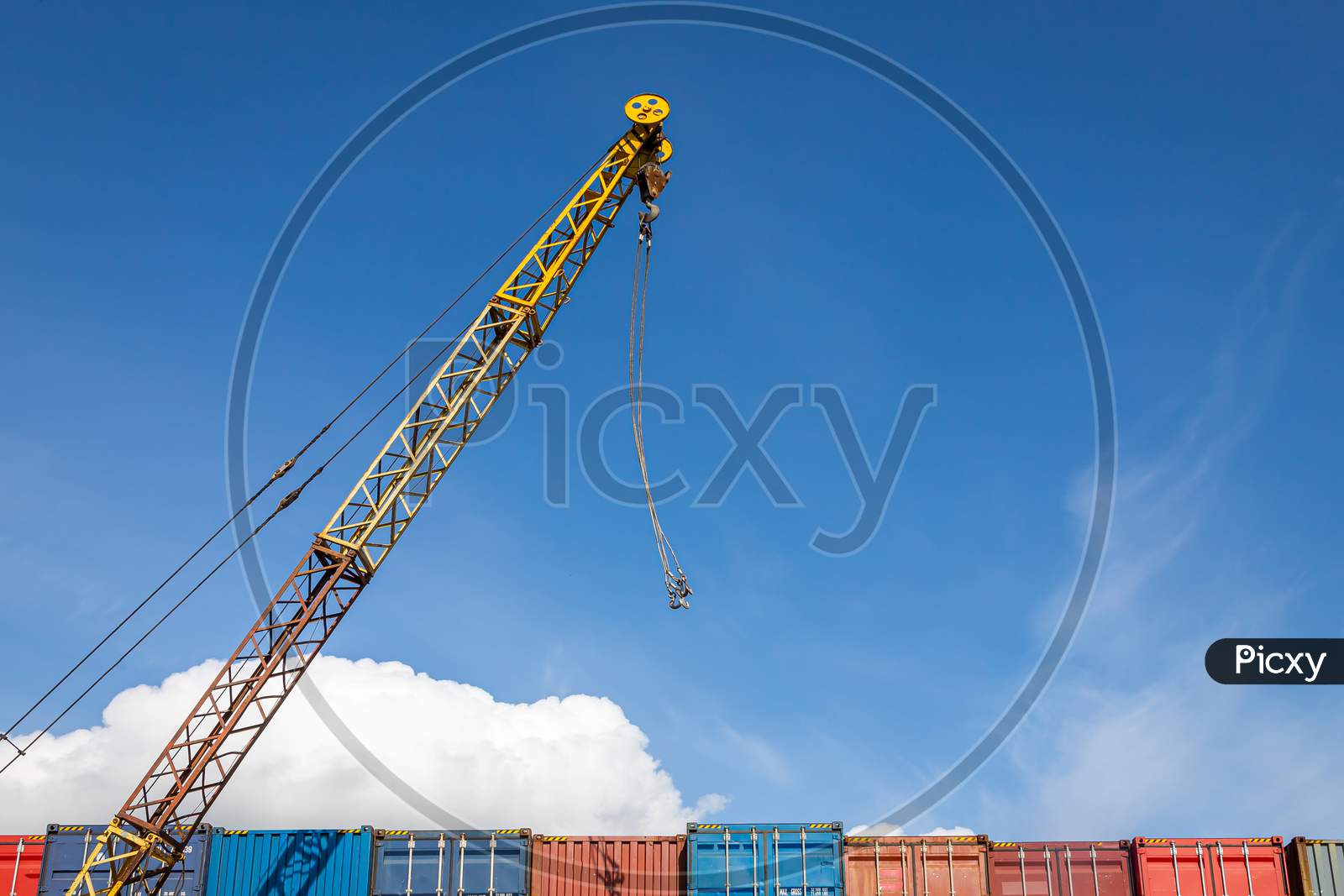 A Cargo Crane Operates In The Territory Of The Container Freight Yard: A Lot Of Metal Containers For Storing Goods Of Different Colors, Stacked In Rows On Top Of Each Other.