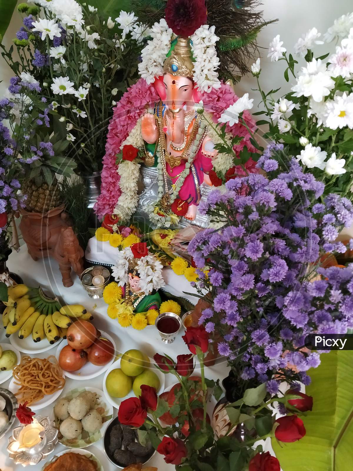 celebrating the Ganesh Chaturthi festival in a home decorated with garland flowers, lamps, fruits... Vinayaka Chaturthi,  Ganapati pooja, and Gowri Habba