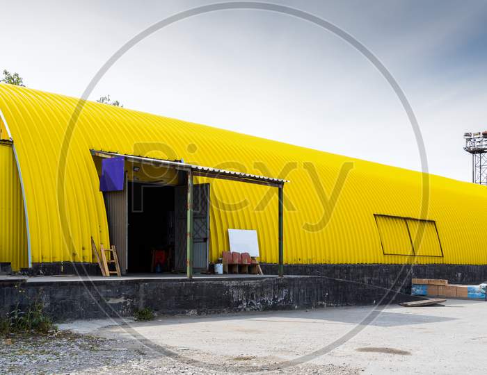 Facade Of A Yellow Metal Warehouse, Commercial Building For Storage Of Goods. The Concept Of Storage Of Goods By Importers, Exporters, Wholesalers, Transport Enterprises, Customs