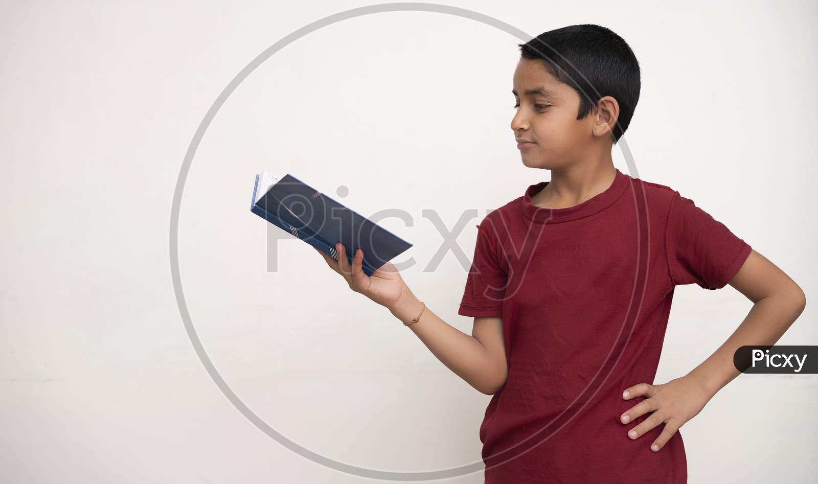 Young Indian Kid Standing On A White Isolated Background With A Book In His Hands. Education And Fun Concept.