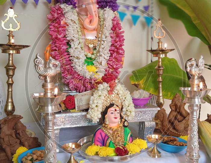 celebrating the Ganesh Chaturthi festival in a home decorated with garland flowers, lamps, fruits... Vinayaka Chaturthi,  Ganapati pooja, and Gowri Habba