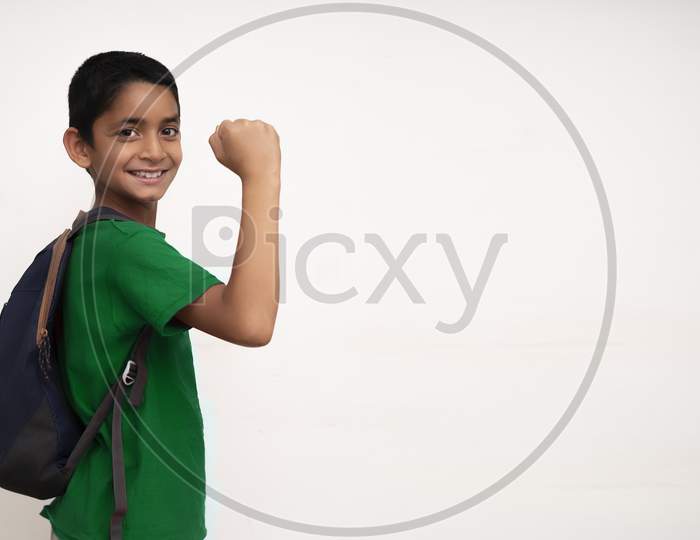 Banner Image Of An Indian Happy Kid Going To School With His Bag On His Back And Showing His Arms On A White Wall With Copy Space.