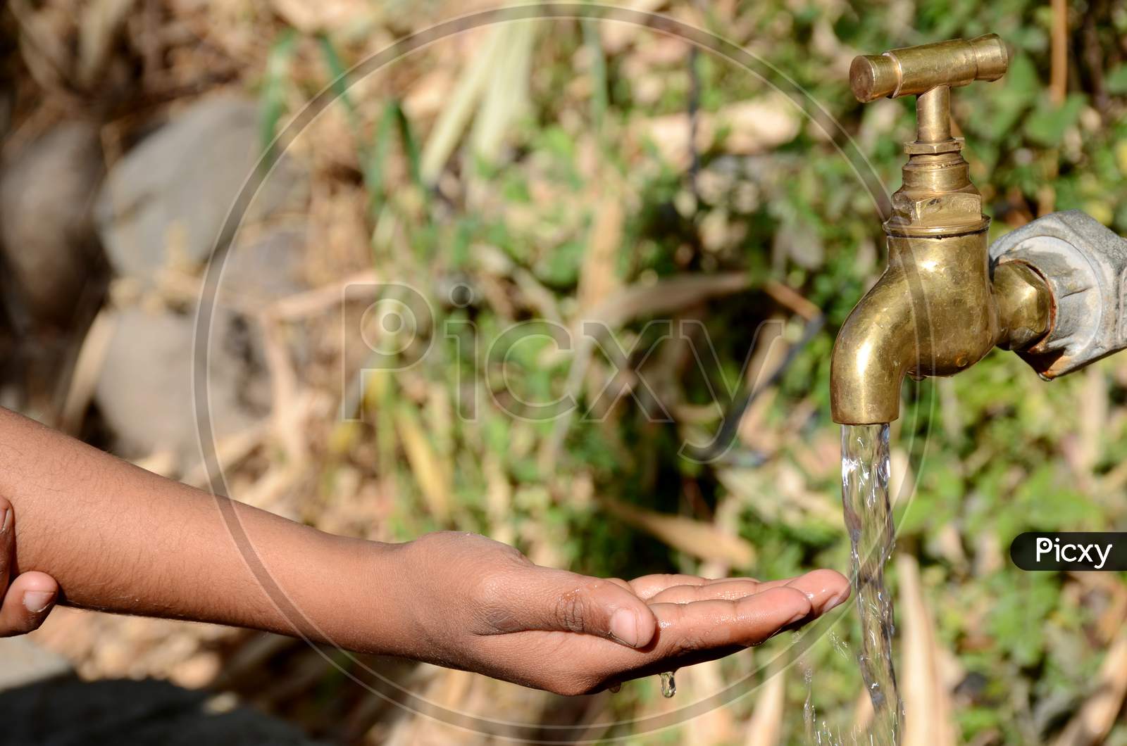 The White Tap Water With Hand Concept World Water Day Over Out Focus Green Brown Background.