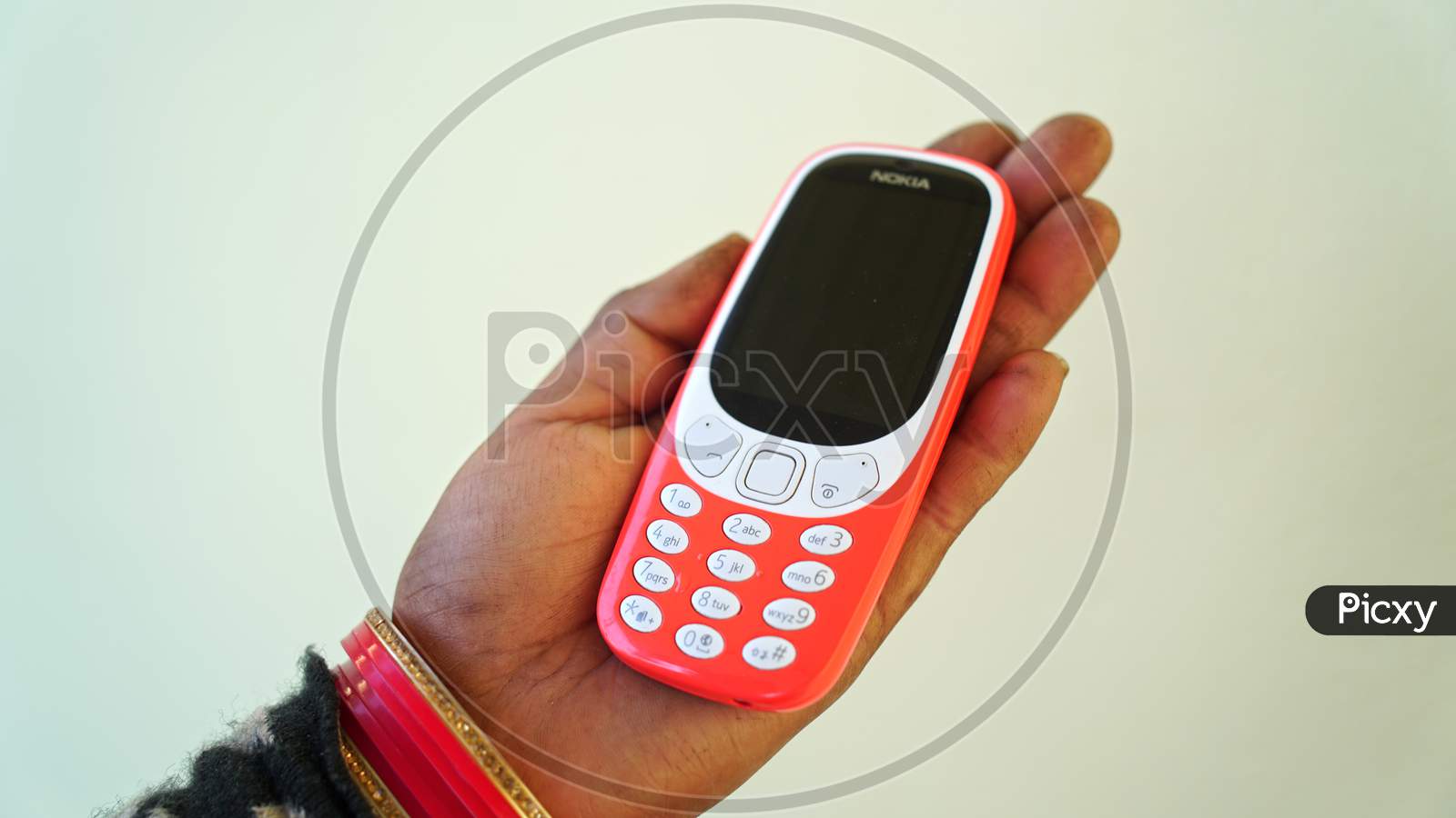 Old 2G Mobile Phone Holding In Woman Hand With Attractive Red Color. Modern Mobile Phone With Attractive Keypad.