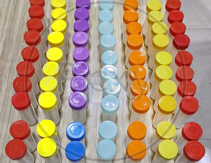Homoeopathy medicine two drachm plastic bottles with colorful caps lined up in rows on clinic wood table, top angle view