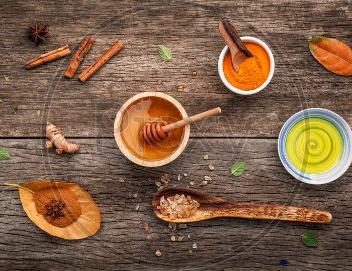 Composition Of Nature Spa Ingredients On The Dark Wooden Table. Spa And Wellness With Honey ,Herbal Compress Ball,Turmeric,Cinnamon Powder ,Cinnamon Sticks ,Aromatic Oil And Star Anise.