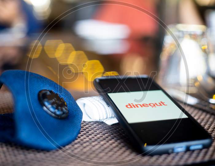 Blue Cloth Mask With Mobile Phone At Side With A Zomato Dineout In Restaurant Showing The Popularity Fo Safe Eating Out And Ordering In As Coronavirus Cases Increase