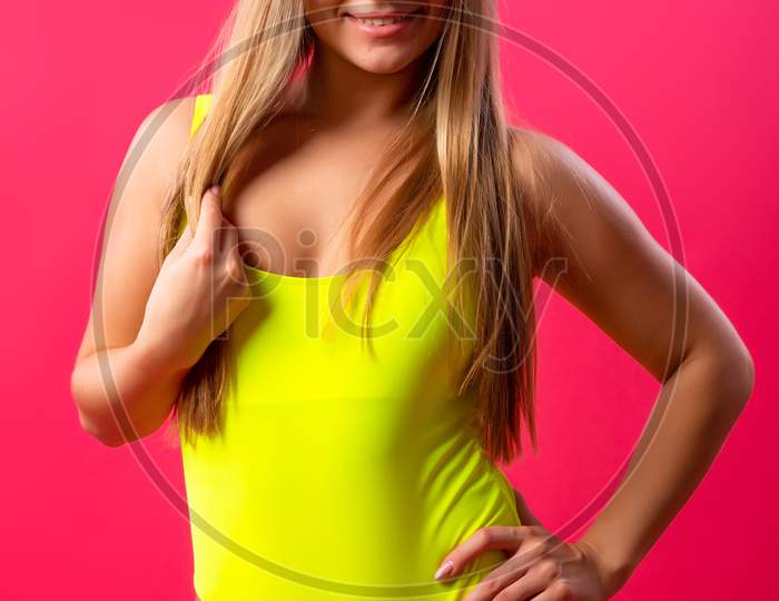Blissful Attractive Woman With Flowing Hair Laughs During A Photo Shoot. Graceful Sweet Girl In Romantic In A Yellow Swimsuit  Enjoying Free Time In The Studio On Isolated Pink Background. Joyful Mood
