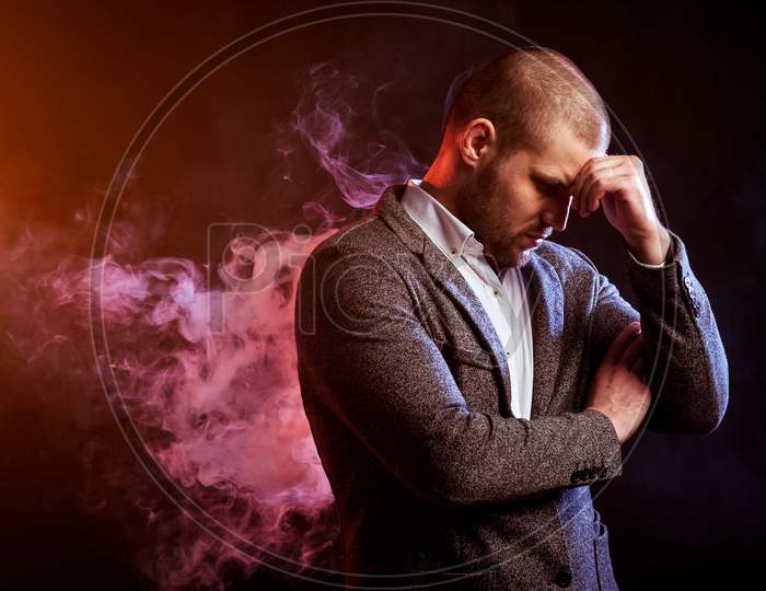 Young Handsome Man Manager In White Shirt And  Gray Suit Standing And Thinking Against Red Smoke From A Vape  On Black Isolated