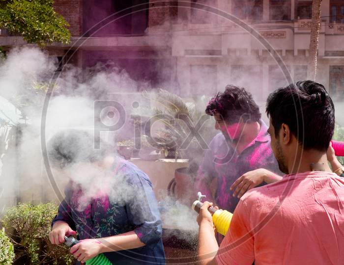 People, Men Women Throwing Colorful Dust Powder At Each Other On The Indian Hindu Festival Of Holi While Playing Safely During The Pandemic