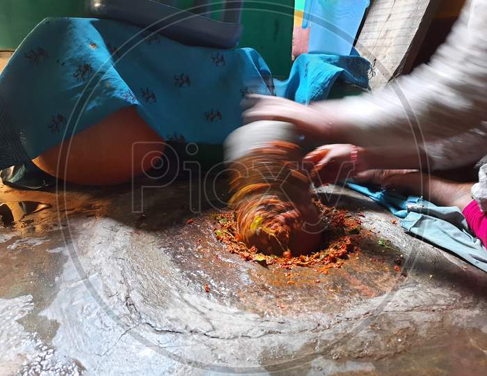 Closeup Indian Girl grinding Masala or Chutney in a traditional way using grinding stones