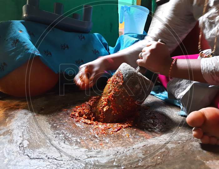 Closeup Indian Girl grinding Masala or Chutney in a traditional way using grinding stones
