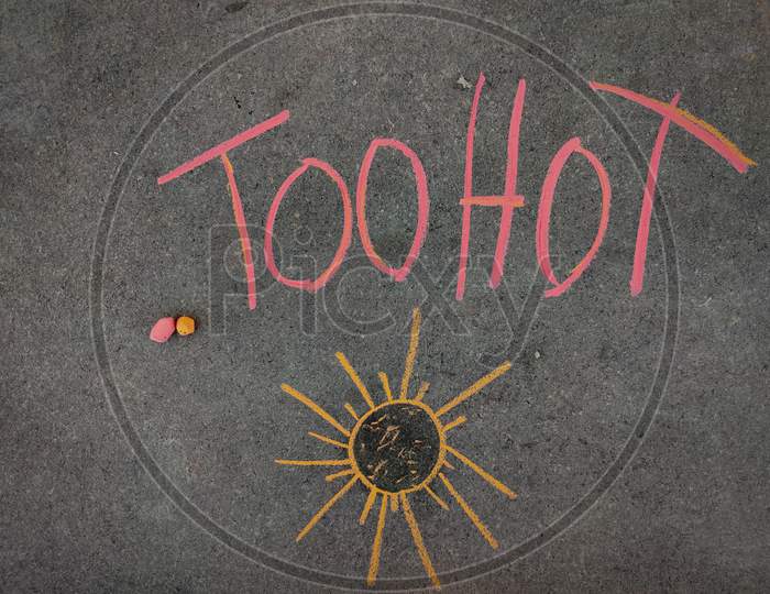 The Inscription Text On The Grey Board, Too Hot With Hand Drawn Sun. Using Color Chalk Pieces.