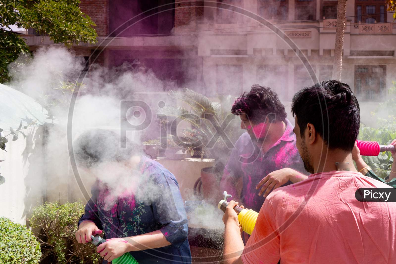 People, Men Women Throwing Colorful Dust Powder At Each Other On The Indian Hindu Festival Of Holi While Playing Safely During The Pandemic