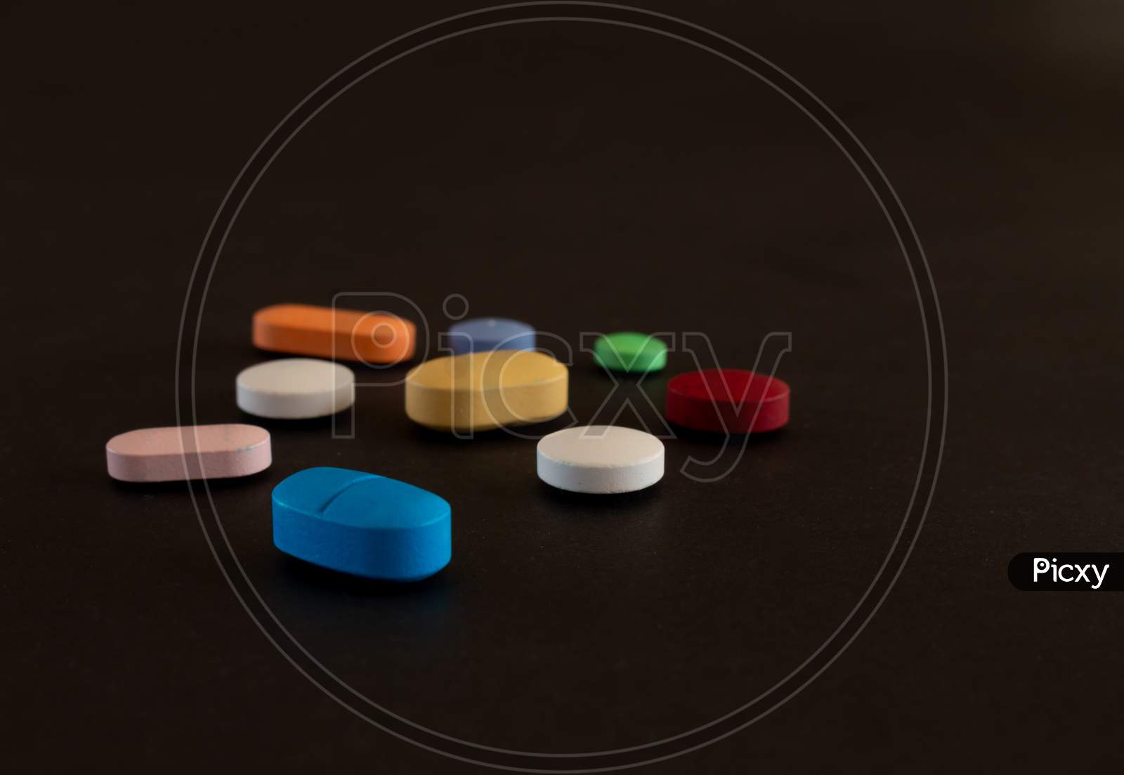 Pills Of Colors On A Neutral Black Background. Selective Focus Of Legal Drugs