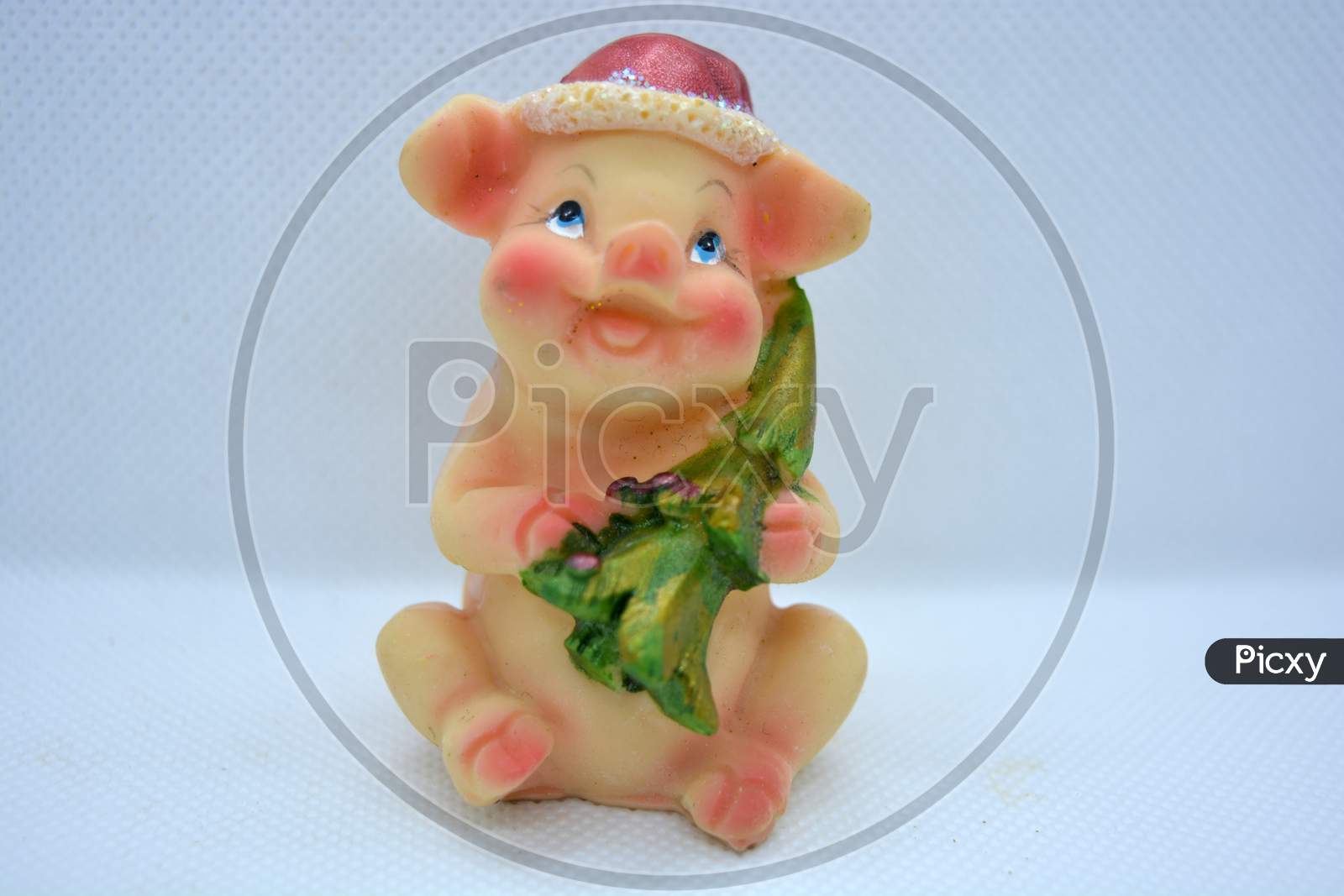 Bright and colorful figurine of a cheerful joyful piglet in a red Christmas hat and a bright green christmas tree in her hands.