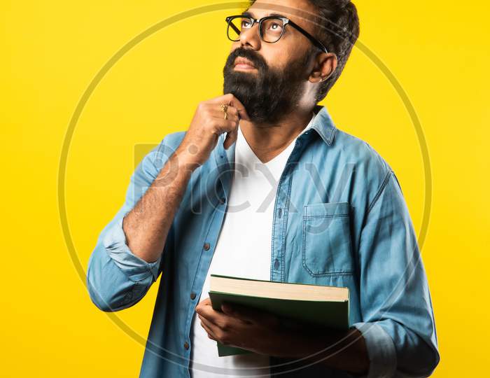 Indian Asian Bearded Man Reading Or Holding Book Against Yellow Studio Background