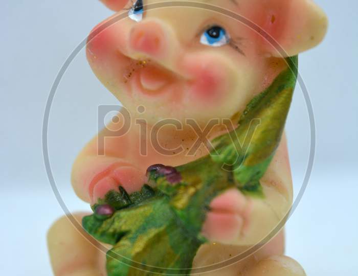 Bright and colorful figurine of a cheerful joyful piglet in a red Christmas hat and a bright green christmas tree in her hands.