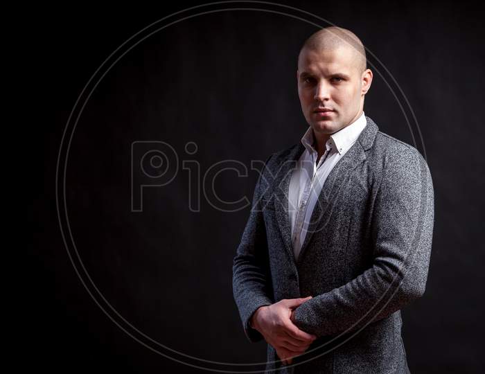 Young Bald Man In White Shirt, Gray Suit Confidently Looks At Camera And Posing On Black Isolated Background
