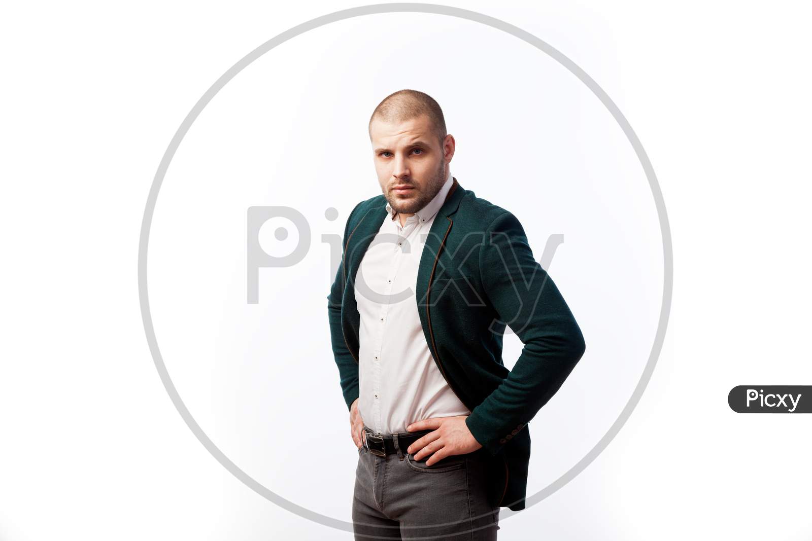 A Young Bald Man In A White Shirt, Green Suit Confidently Looks At The Camera And Holds His Hands On His Jacket On A White Isolated Background, Side View