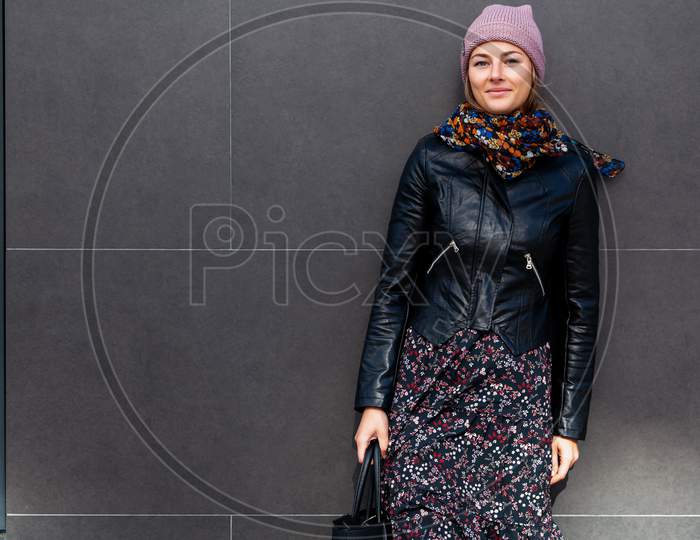 Beautiful Modern Urban Young Woman Wearing Pink Knitting Hat, Black Coat And Dress. Trendy Teenage Girl In Autumn Outdoors.