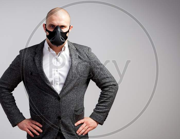 A Young Bald Man In A White Shirt, Gray Suit  And Black Trainig Mask Posing On A White Isolated Background