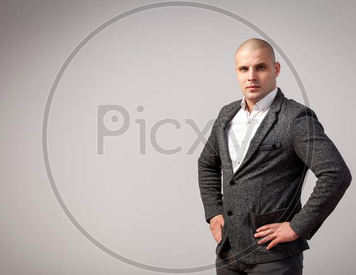 Young Bald Man In White Shirt, Gray Suit Confidently Looks At Camera And Posing On White Isolated Background