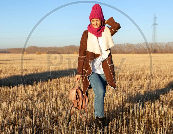 Fashion Lifestyle Portrait Of Young Trendy Woman Dressed In Warm Stylish Clothes And Knitting Hat Laughing And Smiling In The Field.  Portrait Of Joyful Woman