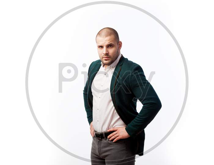 A Young Bald Man In A White Shirt, Green Suit Confidently Looks At The Camera And Holds His Hands On His Jacket On A White Isolated Background, Side View