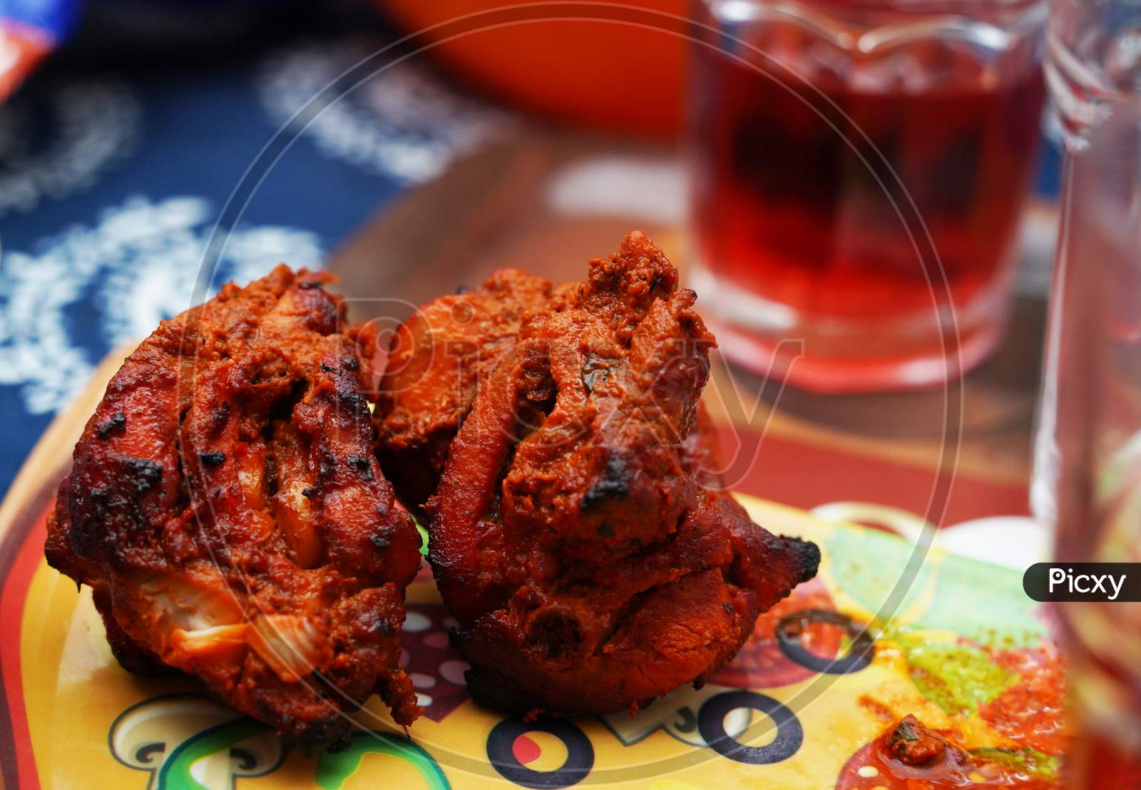 Close Up Image Of A Piece Of Fried And Roasted Chicken Tandoori Breast Piece.Its A Spicy North Indian Starter Dish. Served With Red Cranberry Juice In Glass