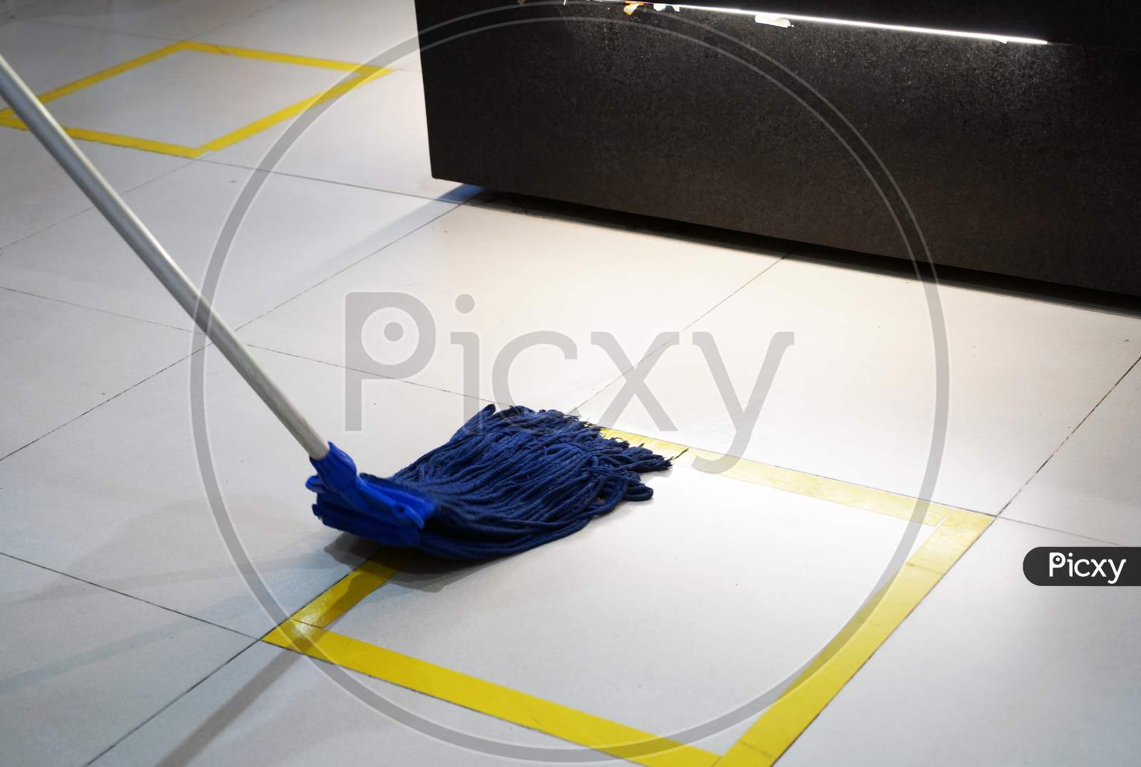 Wiping A Floor With Yellow Stripes, Using A Blue Mop
