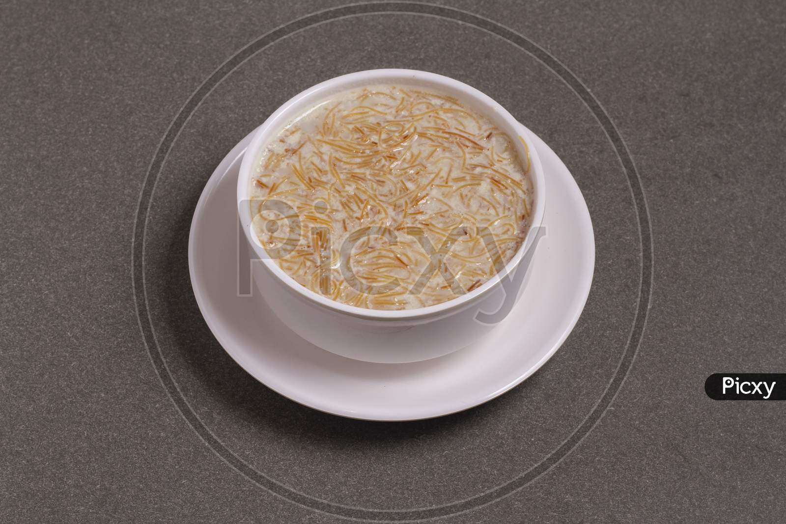 Khir Or Kheer Payasam Also Known As Sheer Khurma Seviyan Consumed Mainly On Eid Or Any Other Festival In India / Asia. Served With Dried Fruit Schnitzel In A Bowl On A Colorful / Wooden Background.