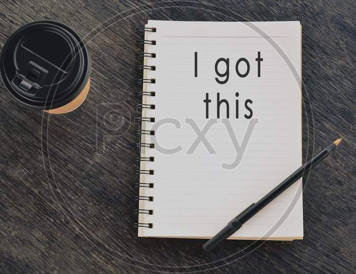 Motivational and inspirational quote on notepad with disposable coffee cup and pen on wooden table