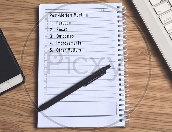 Text on notepad with laptop and smartphone on wooden table. Work habit concept
