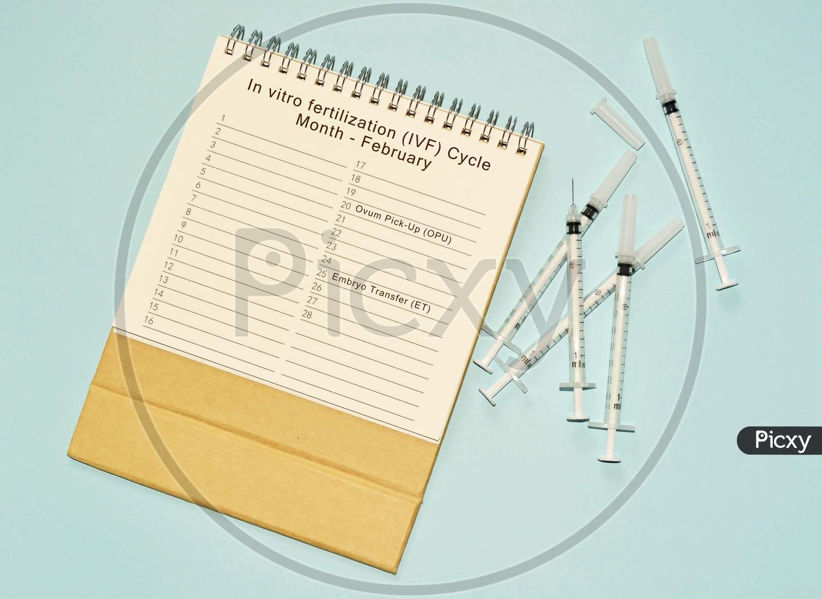 Month of May Doctor's Appointment calendar with disposable injection syringe and medicine on blue background